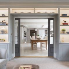 an open living room and dining area with gray painted walls, built in bookcases