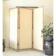 a room divider made out of bamboo with two doors open in front of a potted plant