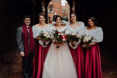 a group of women standing next to each other wearing red dresses and fur stoles