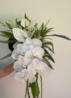 a bouquet of white flowers is held up against a wall by someone's hand