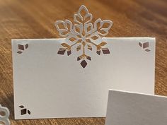 a snowflake cut out of white paper sitting on top of a wooden table