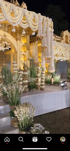 an outdoor wedding setup with white flowers and chandeliers on the stage at night