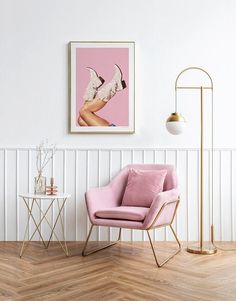 a pink chair sitting in front of a white wall next to a table with a lamp