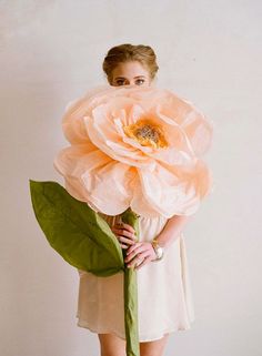 a woman holding a large flower in her hands