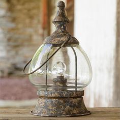 an old fashioned glass lantern sitting on top of a wooden table