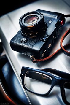 a camera and glasses sitting on top of a metal table next to a pair of reading glasses