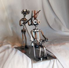 two metal figures sitting on top of a white sheet