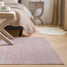 a bedroom with a pink rug and white bedding