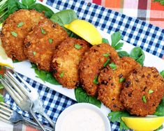 fried crab cakes with lemon wedges on a blue and white checkered table cloth