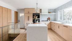 a kitchen with wooden cabinets and white counter tops next to an island in front of a window