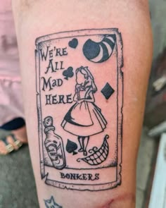 a tattoo with an image of a woman in a dress on her arm and the words, we're all mad here