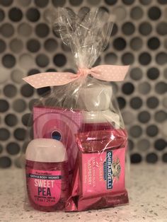 a pink gift basket with body care products and a bow on the top, sitting on a countertop