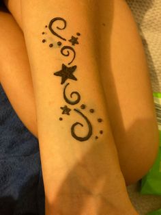 a woman's foot with a tattoo on it that says star and swirls