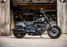 a black motorcycle parked in front of a building with an open garage door behind it