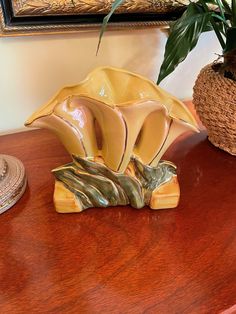 a ceramic flower on a wooden table next to a potted plant