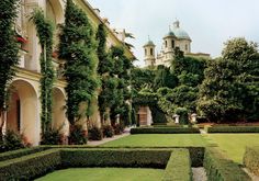 the building has many hedges in front of it and is surrounded by greenery on both sides