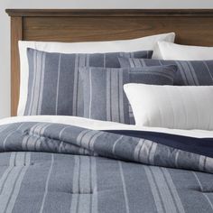 a bed with blue and white striped comforter set on top of the headboard