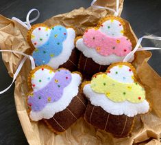 four decorated cookies sitting on top of a piece of wax paper in a brown wrapper