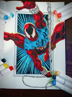 a drawing of a spider - man hanging from a rope, surrounded by crayons