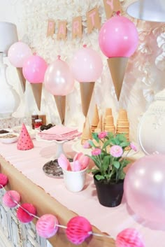 a party table with pink and white balloons, cake pops, ice cream cones, and flowers