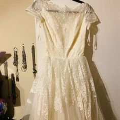 a white dress hanging on a wall next to other jewelry and accessories in a room