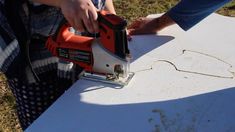 a person using a power tool to cut out a piece of paper with a cordless jig saw