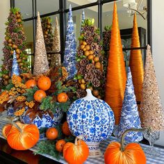 a table topped with blue and white vases filled with pumpkins