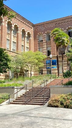 an old brick building with stairs leading up to the front door and palm trees on either side