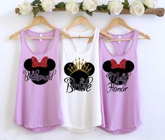 three shirts hanging on a rack with flowers in front of them and one is wearing a tiara