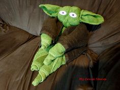 a green stuffed animal laying on top of a brown couch