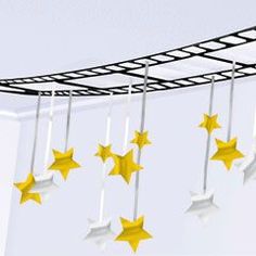 five gold stars hanging from the ceiling in front of a white wall and metal bars