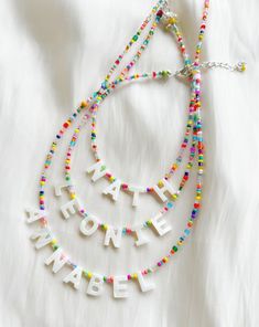 three necklaces that say happy new year and have beads hanging from the neckline