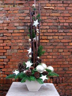 a white vase filled with christmas decorations on top of a wooden table next to a brick wall