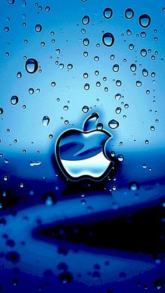 an apple logo is shown on the glass surface with water droplets surrounding it and blue sky in the background