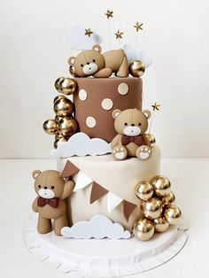 a three tiered cake decorated with teddy bears and gold foil balloons, on top of a white plate