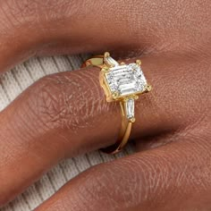 a woman's hand with a diamond ring on top of her finger and an engagement band