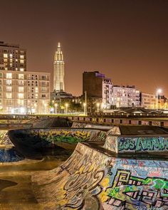 a skate park with graffiti on the walls and in the middle of it is a cityscape