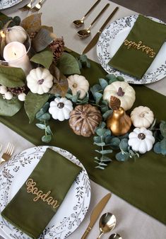 the table is set with green napkins, white plates and gold place settings for thanksgiving dinner