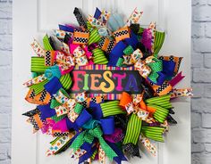 a colorful wreath with the word fiesta written on it is hanging on a white door