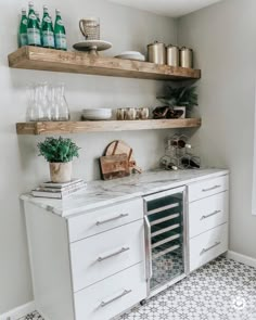 a kitchen with white cabinets and shelves filled with wine bottles, glasses, and other items