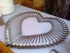 a heart made out of spoons sitting on top of a table next to a cake