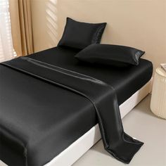 a bed with black sheets and pillows on it