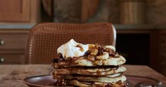 a stack of pancakes topped with whipped cream and walnuts on a plate next to a pair of scissors