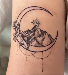 a tattoo with mountains and stars on the side of the moon, as well as flowers