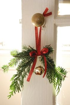 a bell hanging from the side of a door with a red ribbon around it and a bow