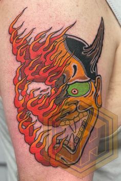 a man with a tattoo on his arm that has flames coming out of the head