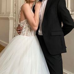 a man in a tuxedo and a woman in a wedding dress pose for a photo