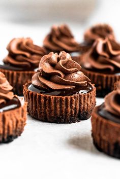 chocolate cupcakes with frosting on top sitting on a white surface, ready to be eaten