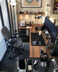 a desk with a computer and headphones on it in front of a large window