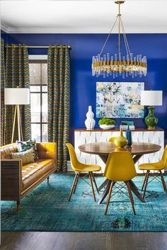 a blue dining room with yellow chairs and a chandelier hanging from the ceiling